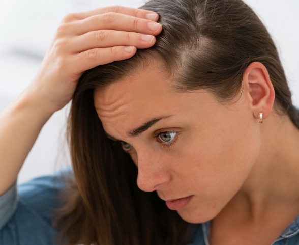 Alopecias más frecuentes en medicina estética: androgenética, areata, efluvio telógeno y otras patologías del cuero cabelludo 2 Mujer observando la pérdida de densidad capilar en su línea de implantación