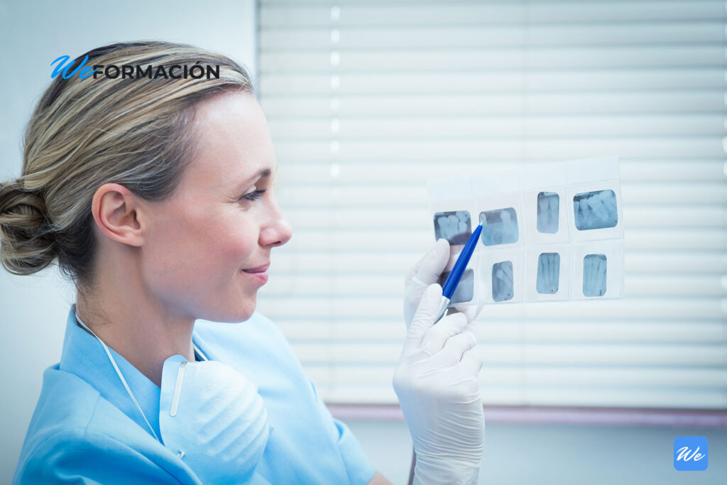 Odontóloga revisando una serie de radiografías dentales en la consulta