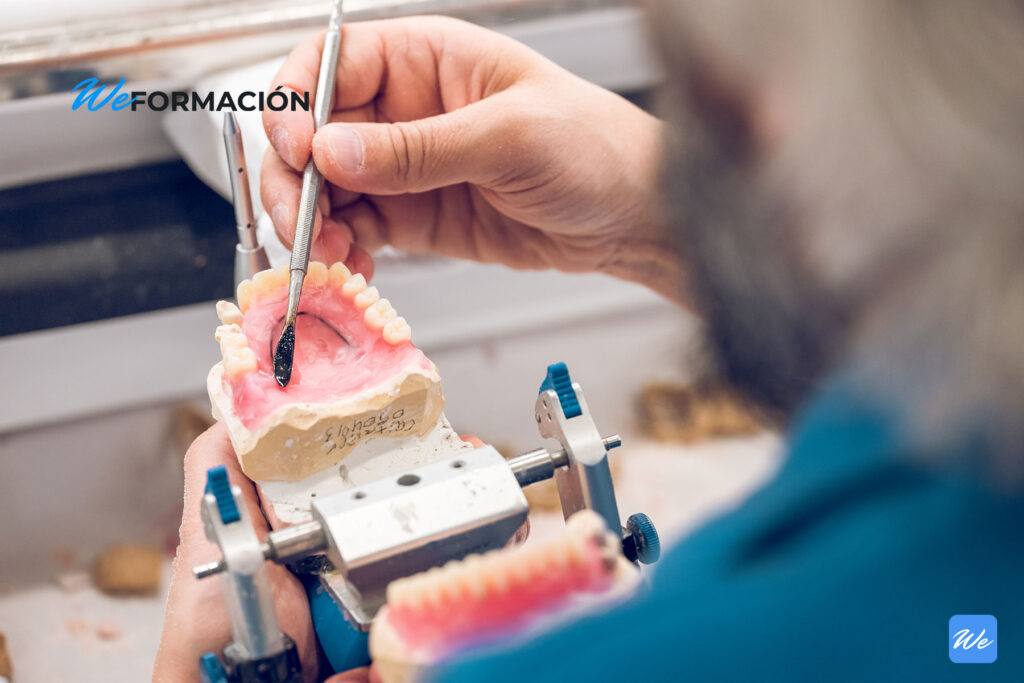 Protésico dental modelando una prótesis removible sobre un articulador en el laboratorio