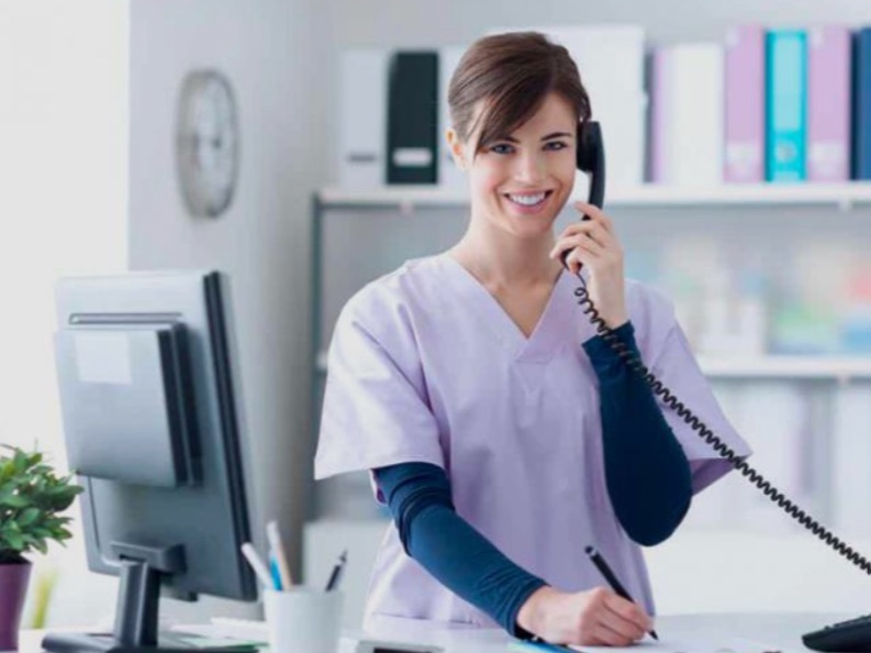 Comunicación interpersonal en clínicas y centros de salud: habilidades sociales, lenguaje no verbal y atención al paciente 1 Recepcionista de clínica atendiendo una llamada de teléfono mientras toma notas